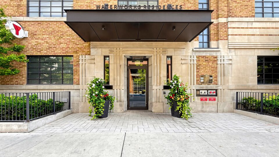 Waterworks Residences entrance with a stone surround, black canopy and planters either side of the door