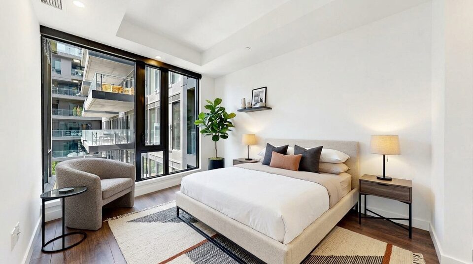 Primary bedroom virtually staged with a bed, armchair and side table by the window